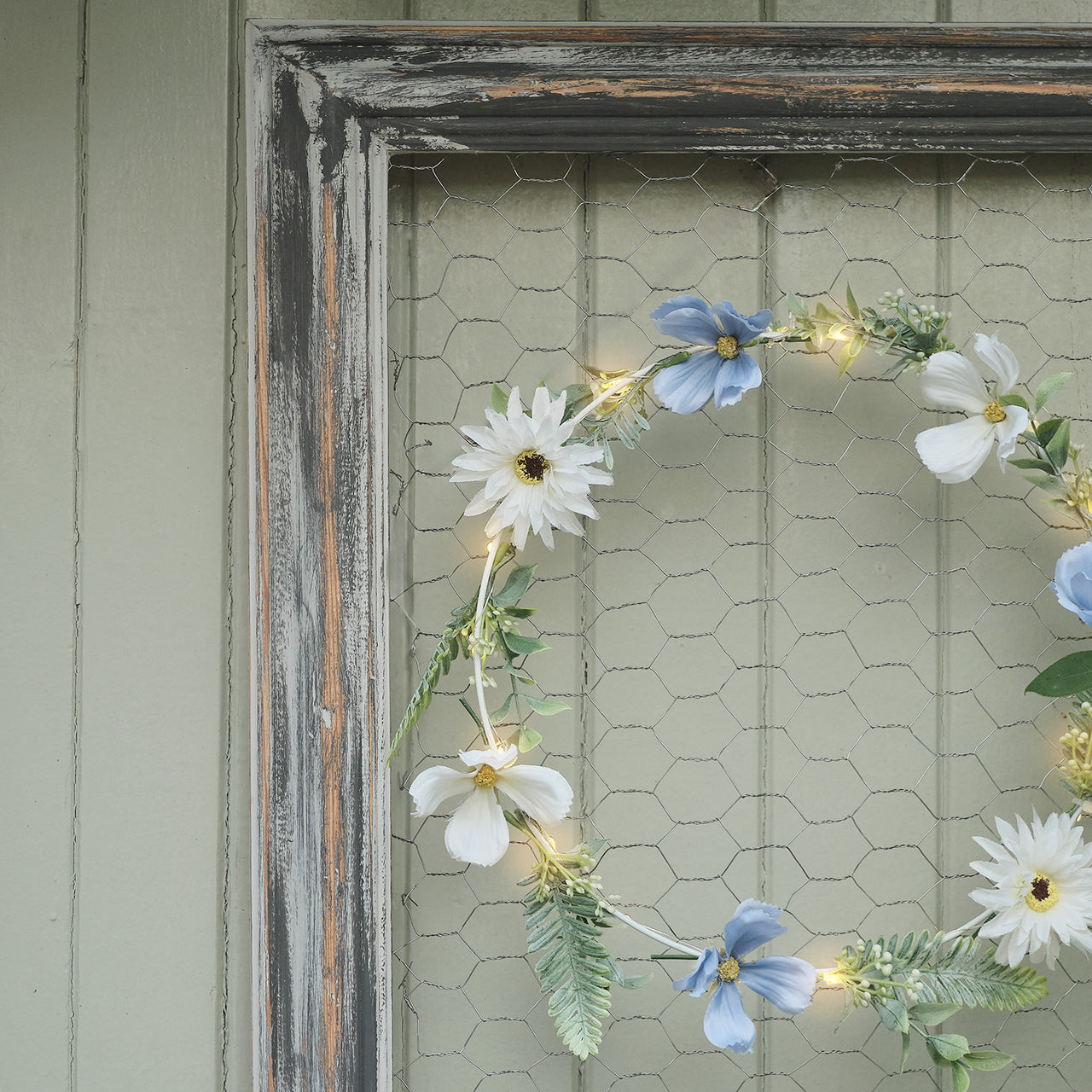 Beleuchteter Kranz und Girlande mit blauen und weißen Blüten