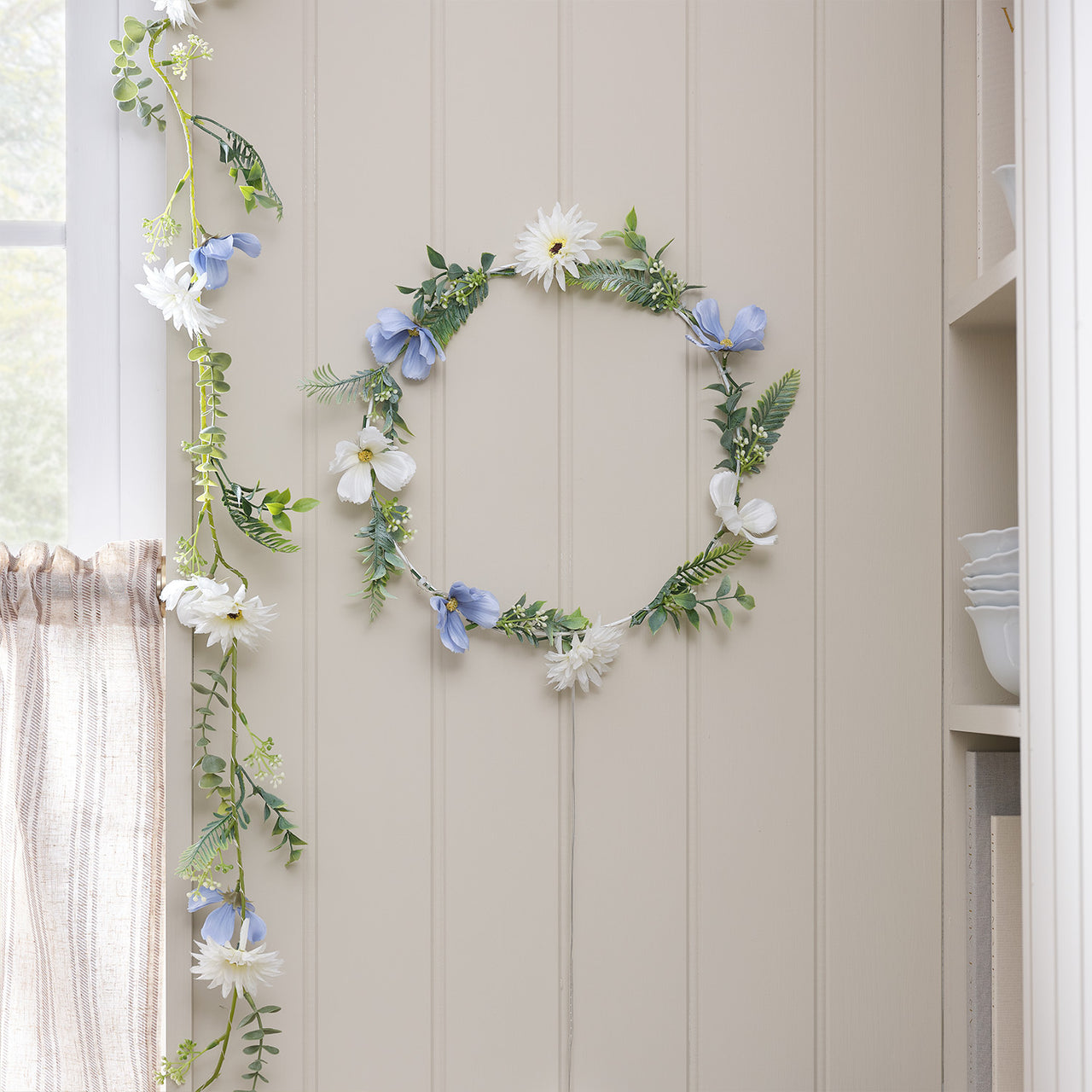 Beleuchteter Kranz und Girlande mit blauen und weißen Blüten indoor