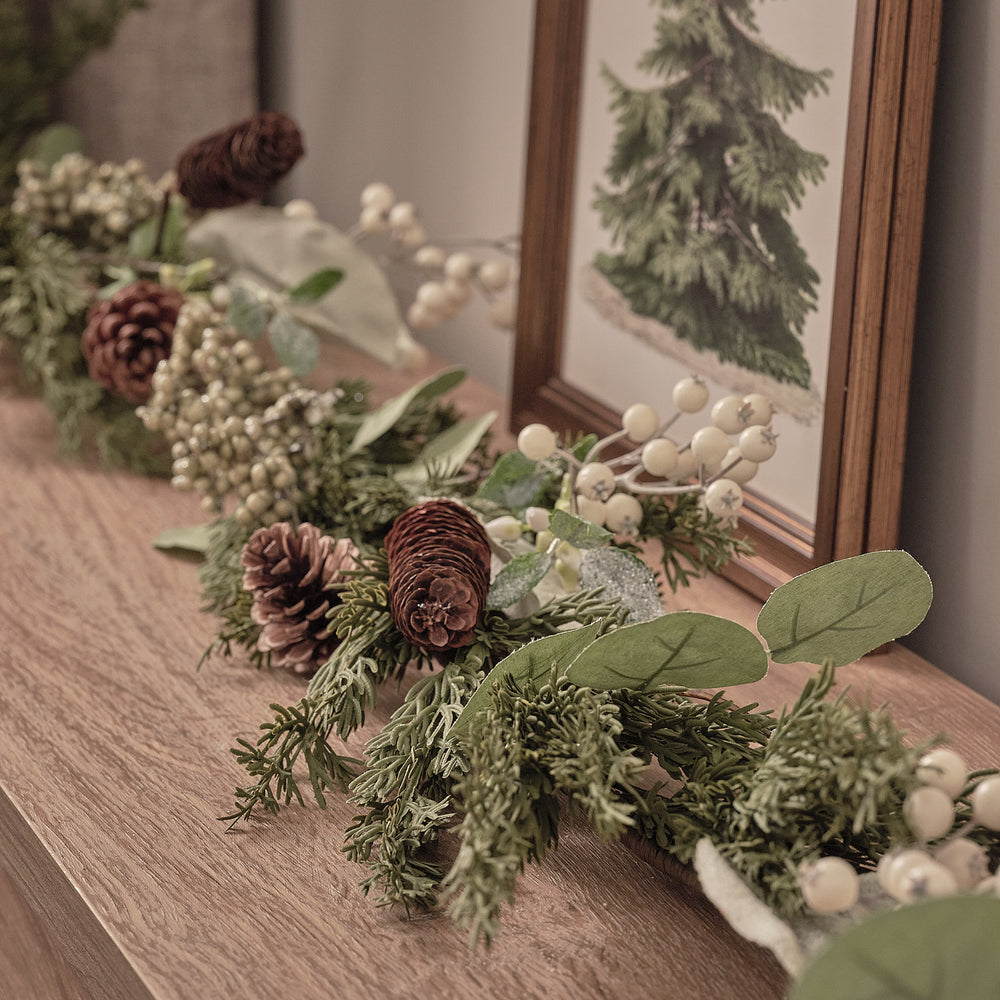 Weihnachtskranz und Girlande mit weißen Beeren und Tannenzapfen
