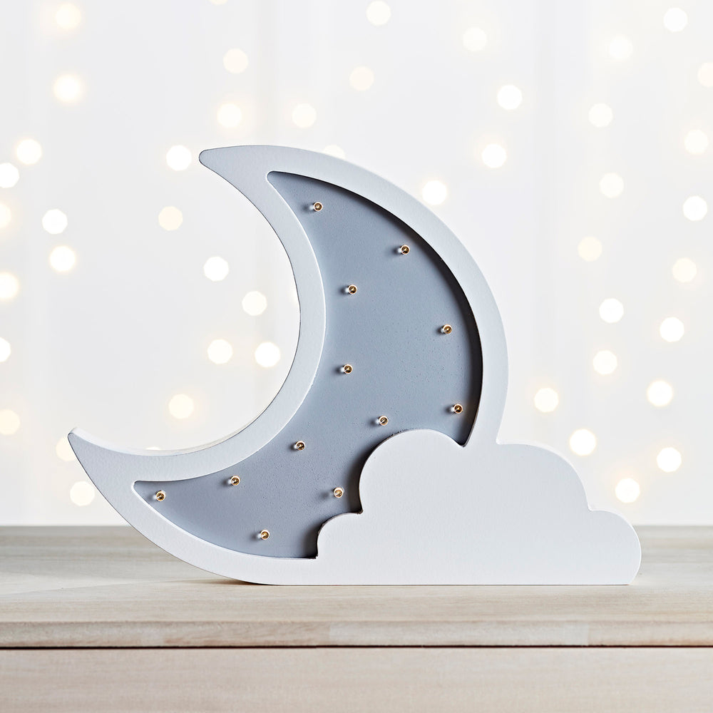 Ausgeschaltete Mondlampe mit Wolke auf Holztisch.