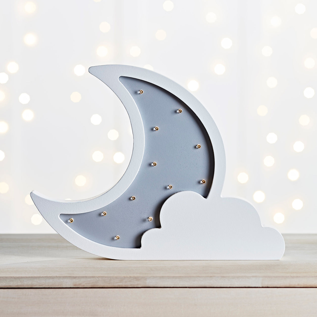 Ausgeschaltete Mondlampe mit Wolke auf Holztisch.