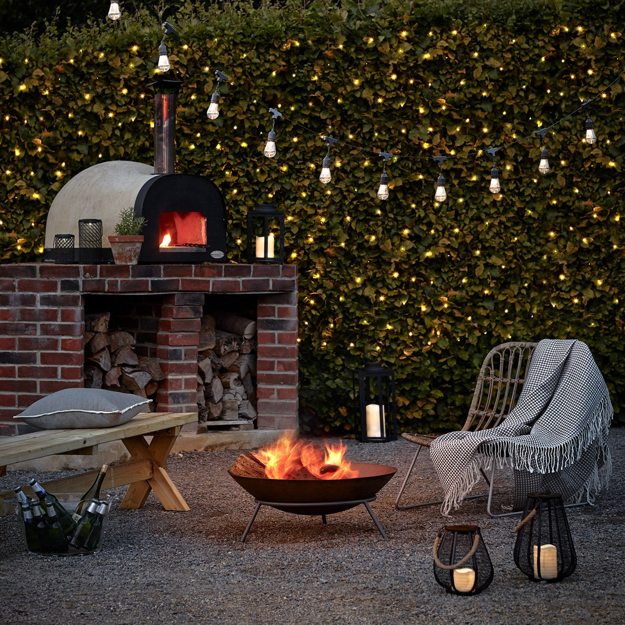 Gartendeko mit Party Lichterkette, Feuer, Lichternetz und Laternen im Dunkeln.